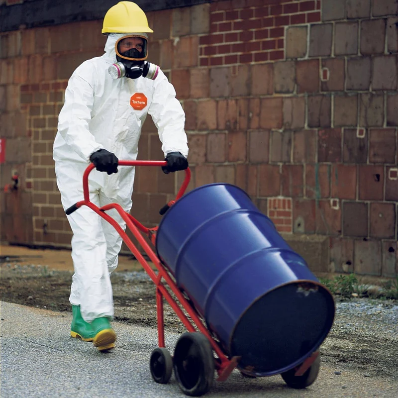 Man wearing Tychem 4000 Coveralls pushing a barrel of chemicals