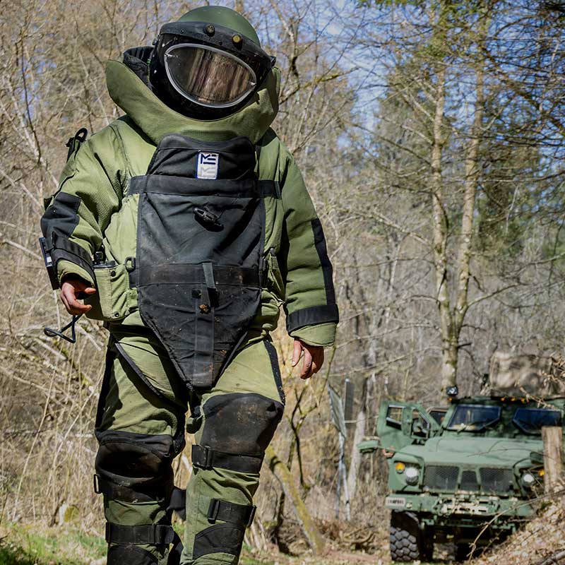 Soldier walking towards explosives while wearing Med-Eng bomb suit