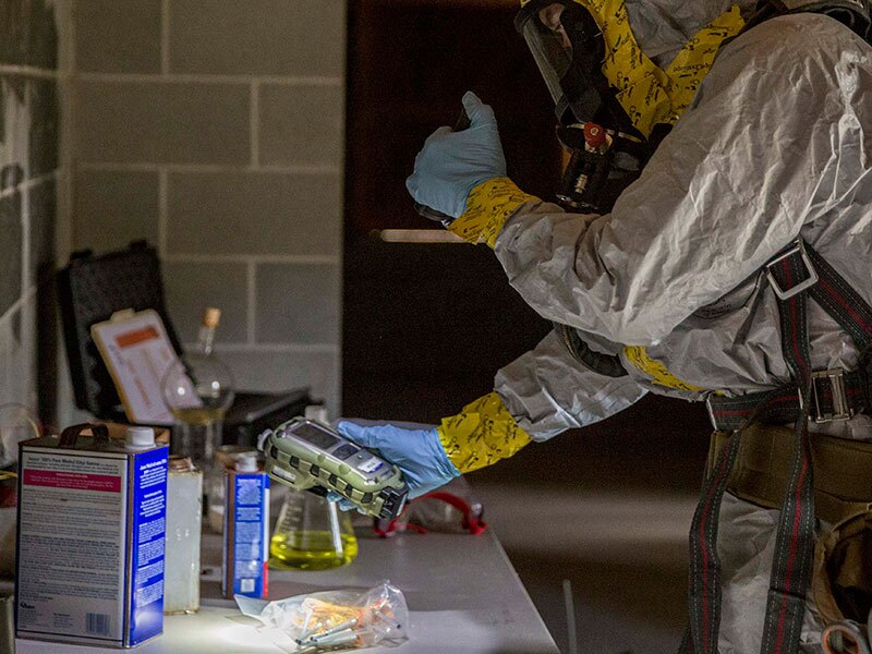 HazMat responder holding MultiRAE Pro and wearing protective chemical clothing