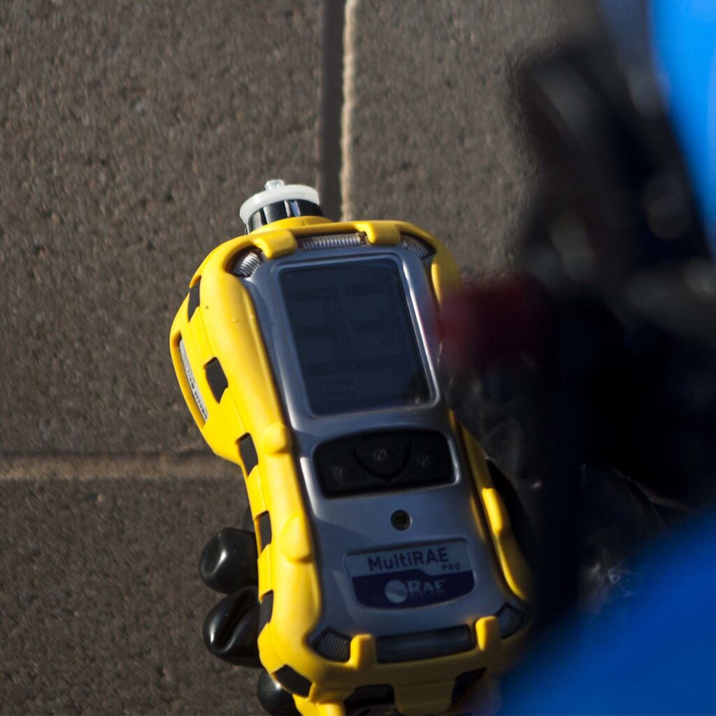 Honeywell RAE Systems MultiRAE Pro held in hand by a user dressed in a hazmat suit