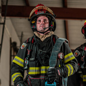Firefighter wearing communication headset while carrying a fire hose.