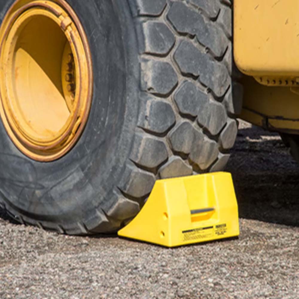 Justrite Checkers Heavy-Duty Chock used to secure a industrial vehicle