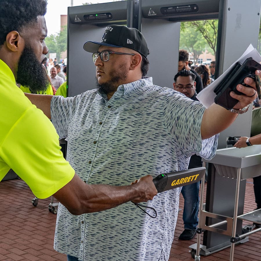 Event Security staff using the Garrett Guide Hand-Held Metal Detector to screen an event attendee